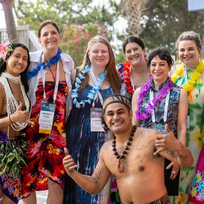 Person wearing a safety hat rappelling over the side of a high rise building with the beach and ocean in the background