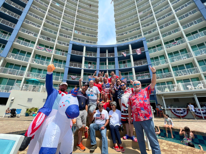 Group of people wearing red, white and blue outfits standing in front of a high rise resort