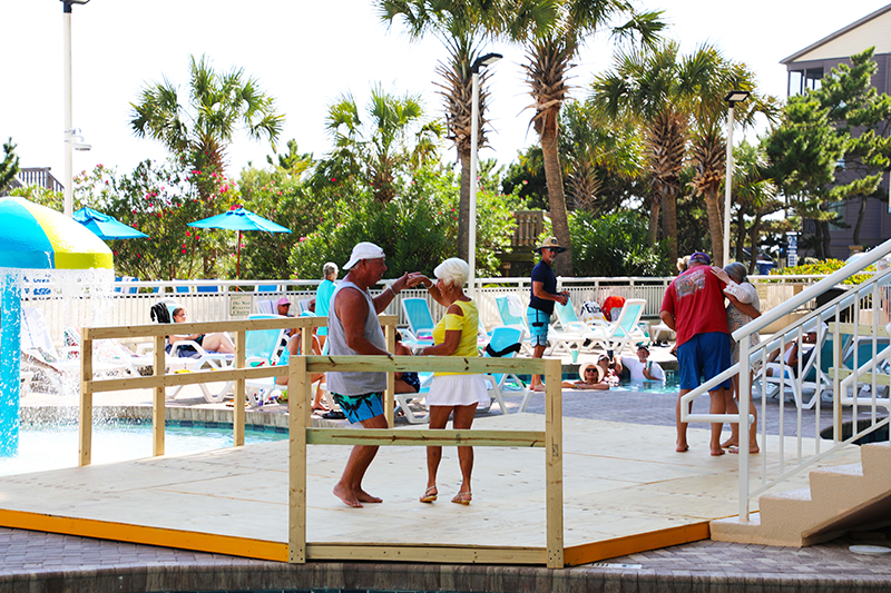 Couple dancing on wooden dancefloor at outdoor pool