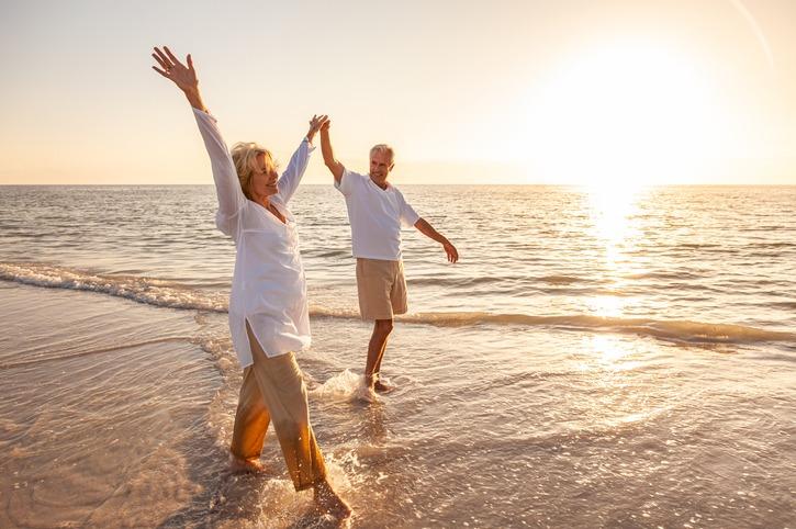 Smiling couple walking on the beach at sunrise
