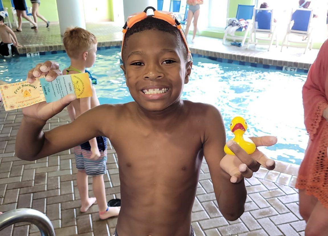 Smiling child holding a rubber duck at the avista resort indoor pool