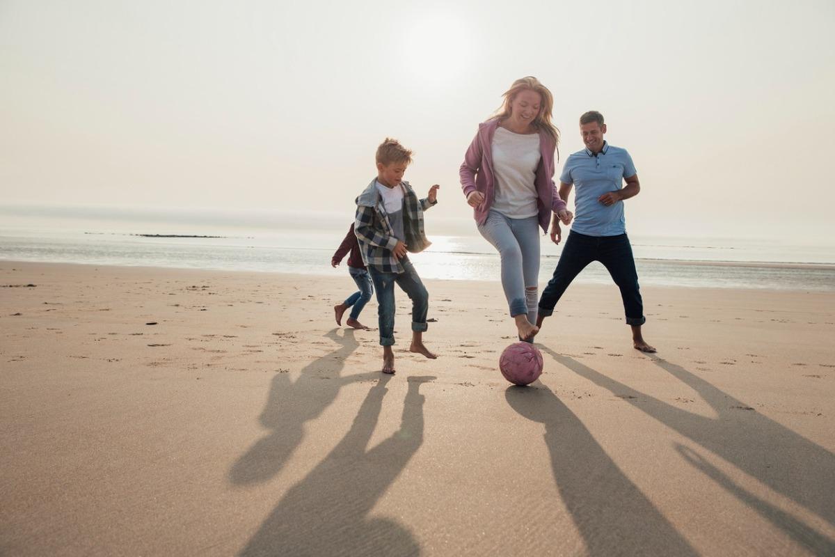 family playing on the beach during the winter months wearing a warm outfit and enjoying the sunshine