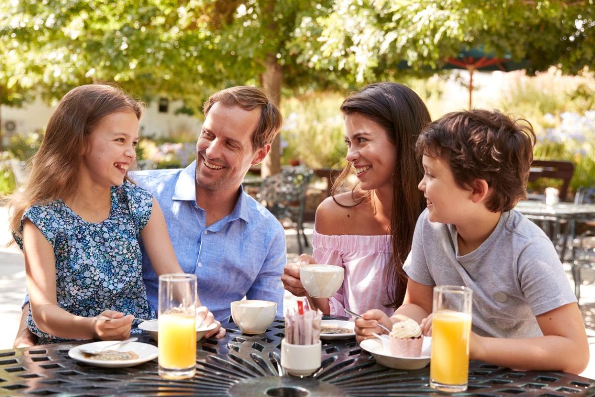 Family Enjoying Snack At Outdoor Cafe Together