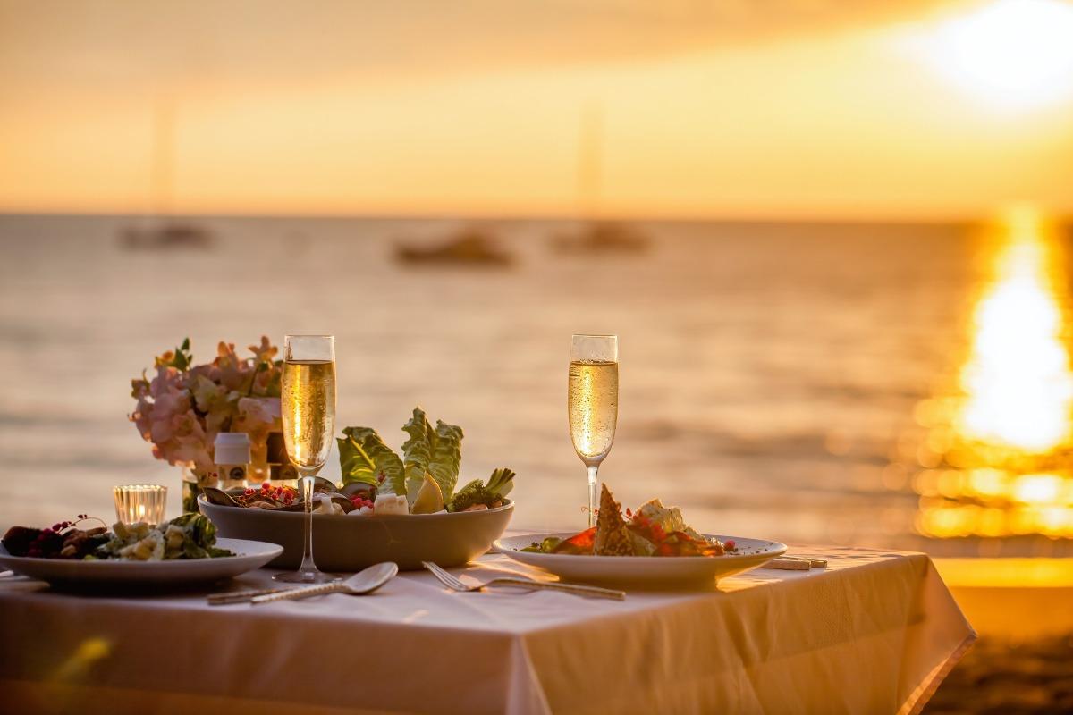 a romantic dinner table set on the beach at sunset