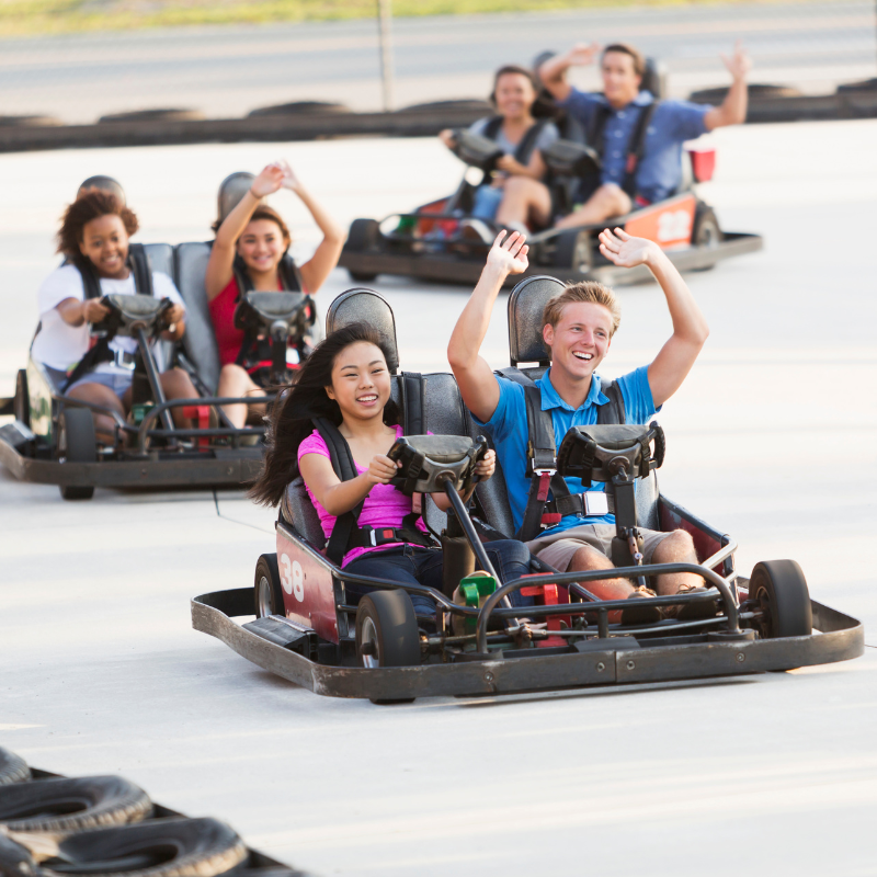 Group of young adults riding in around a race track in go karts