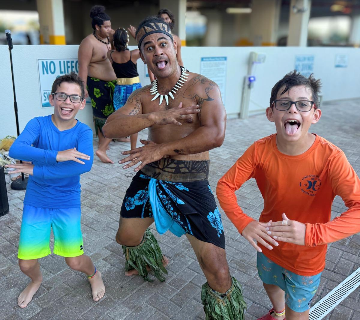 Polynesian dancer performing a haka with two smiling kids