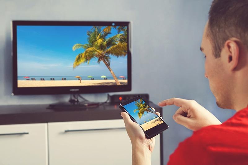 Man syncing a beach image from his phone to the TV screen.