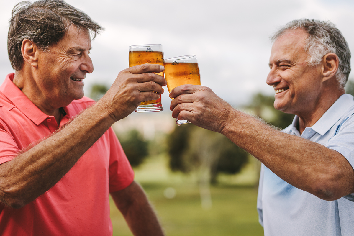 Two men celebrating with beer glasses raised in a toast