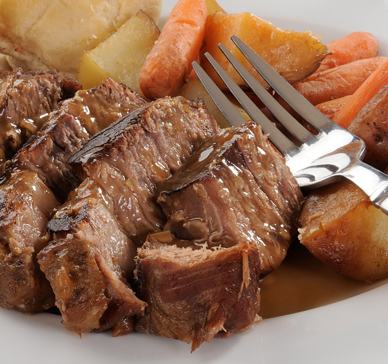 Plate with pot roast, carrots, potatoes and a fork