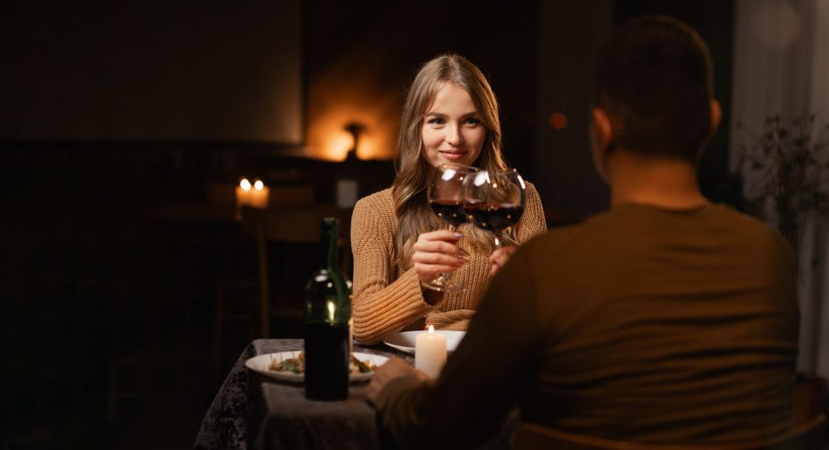 Happy young couple in love drinking wine having romantic dinner, celebrating Valentines Day.