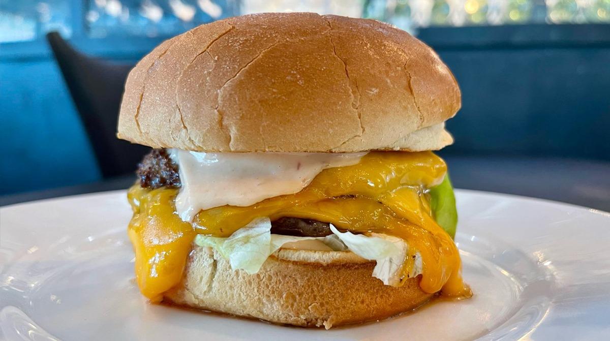 Double patty smashburger with cheese and burger sauce on a white plate at Avista Resort