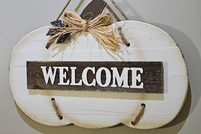 Wooden sign in the shape of a pumpkin that says welcome