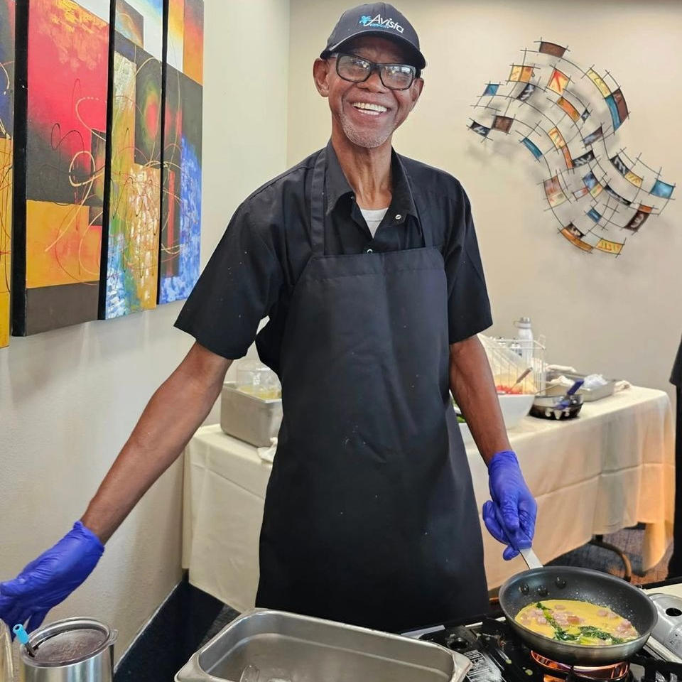 Person wearing a safety hat rappelling over the side of a high rise building with the beach and ocean in the background