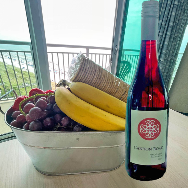 a bottle of wine and a fruit basket with grapes and bananas