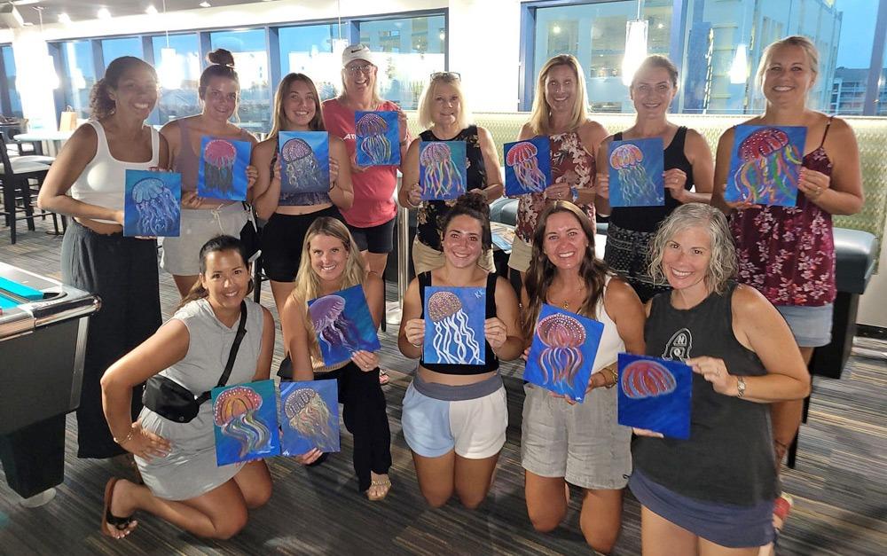 Group of 13 women holding canvases with painted jellyfish design